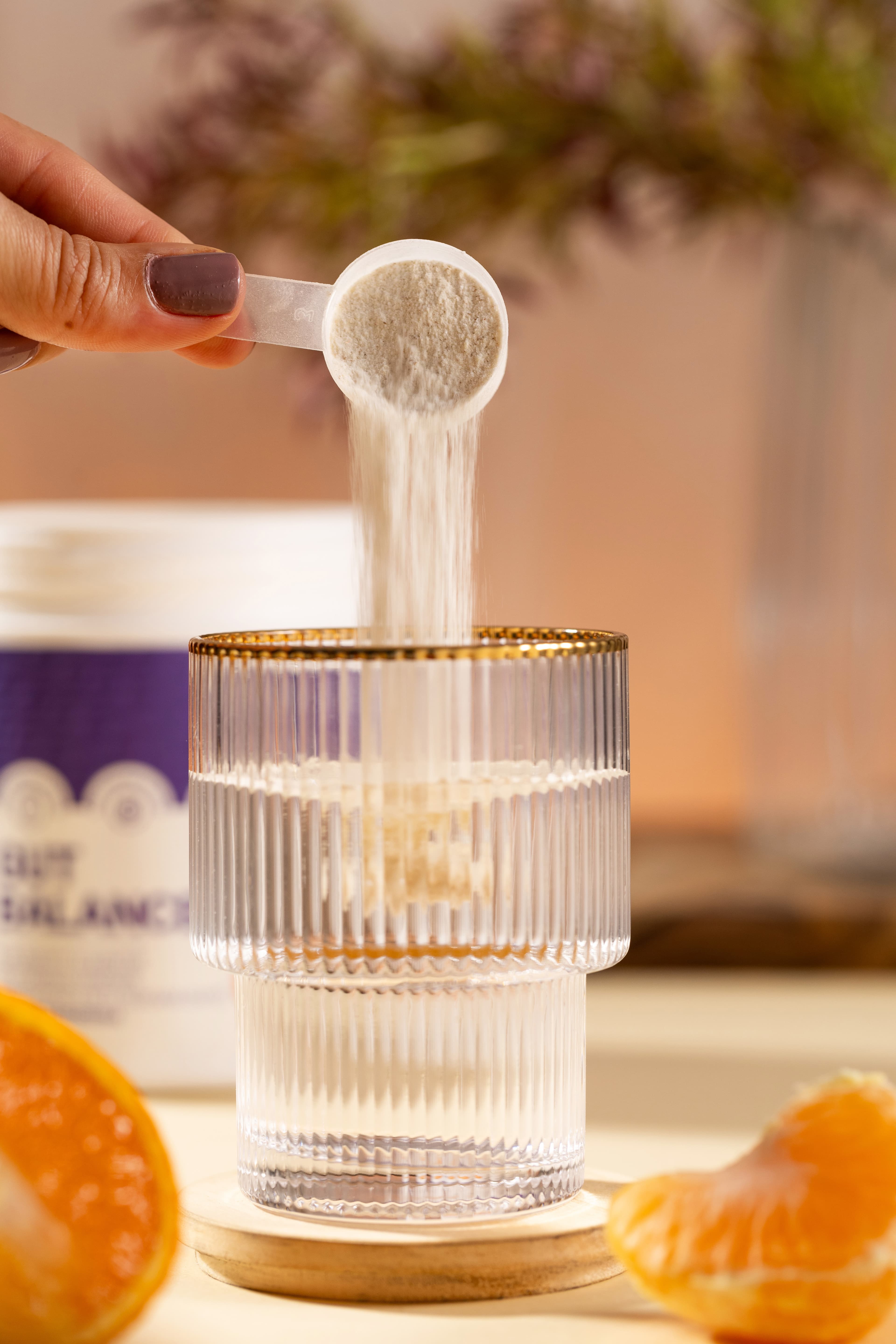 Dose do Gut Balance sendo servida em um copo de água com tangerina ao lado